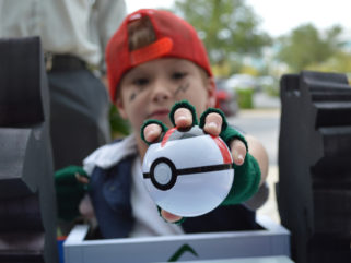 A child dressed as Ash Ketchum holds out a Poke ball