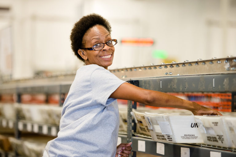 A woman smiles while filing mail.