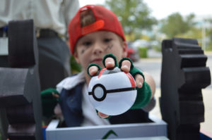 A child dressed as Ash Ketchum holds out a Poke ball