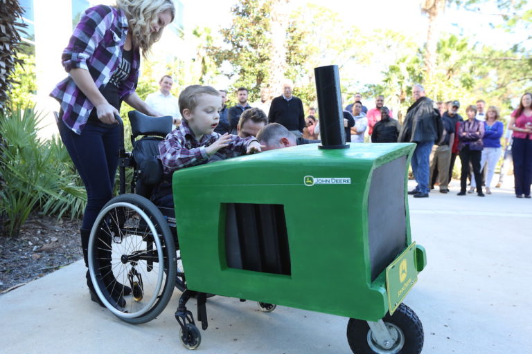 Young boy in wheelchair sits in custom tractor costume.