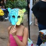 A child holds a jaguar mask over their face.