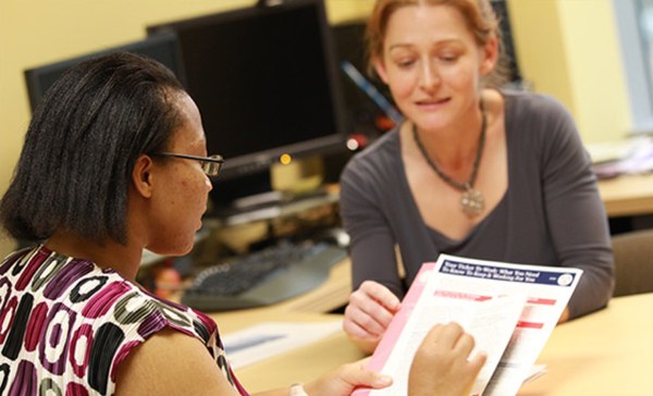 A benefits counselor goes through a Ticket to Work leaflet with a woman at a desk.
