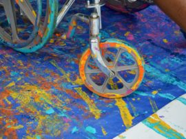 The wheels of a wheelchair covered in paint.