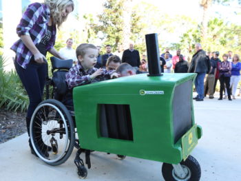 Young boy in wheelchair sits in custom tractor costume.