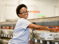 Woman with glasses sorting mail and smiling for a photo