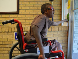 A boy who uses a wheelchair looks outside a door as he opens it.